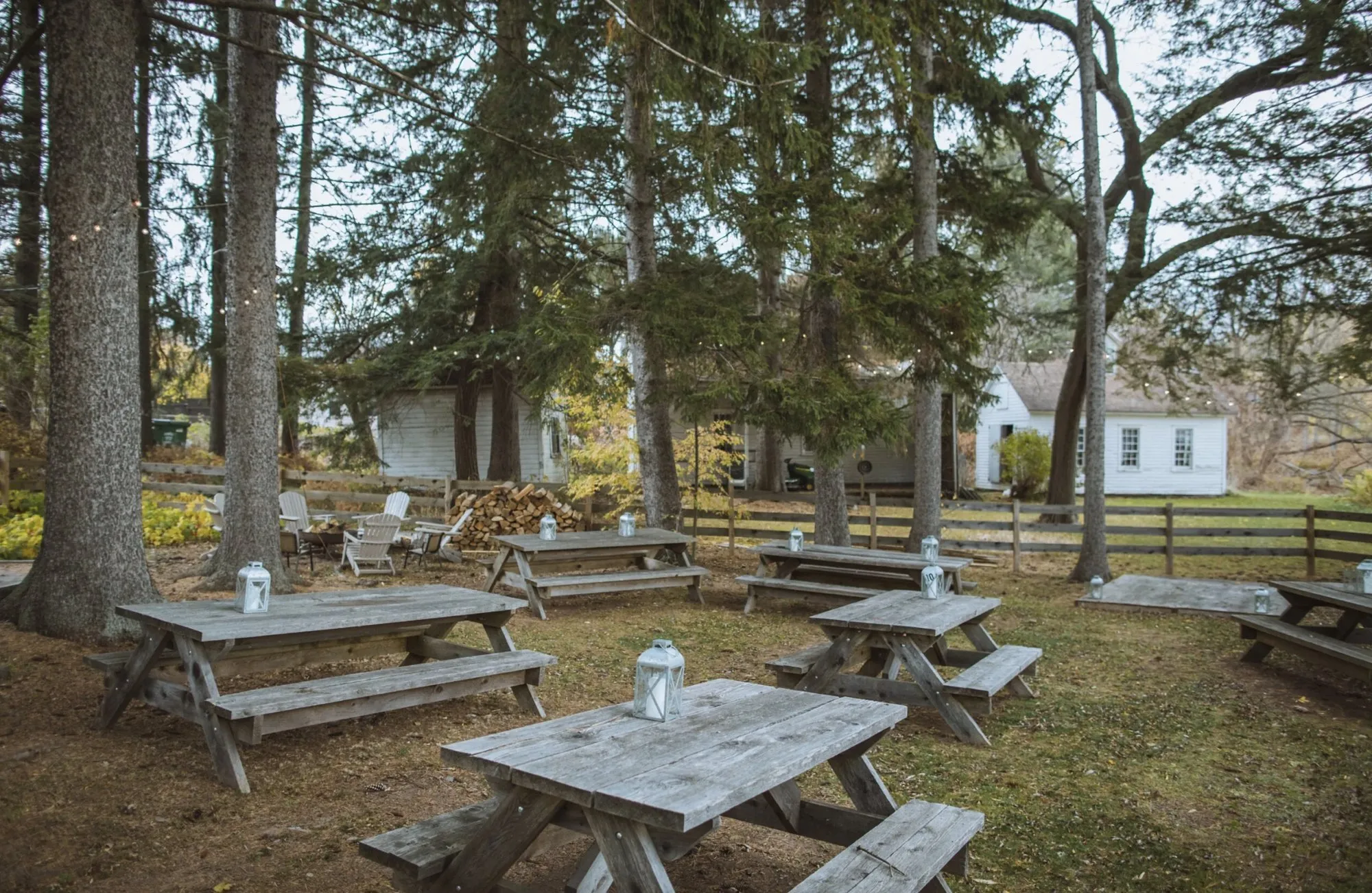Picnic tables with lanterns under the pines at Book Village Inn